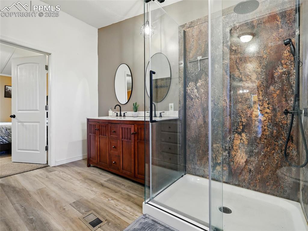Image 15 of 45: En-suite primary bathroom with double vanity, a shower stall, and tile floo