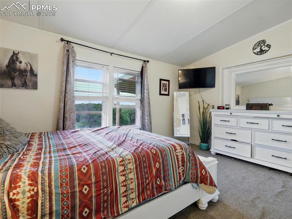Image 18 of 45: Second Bedroom featuring lofted ceiling and carpet floors