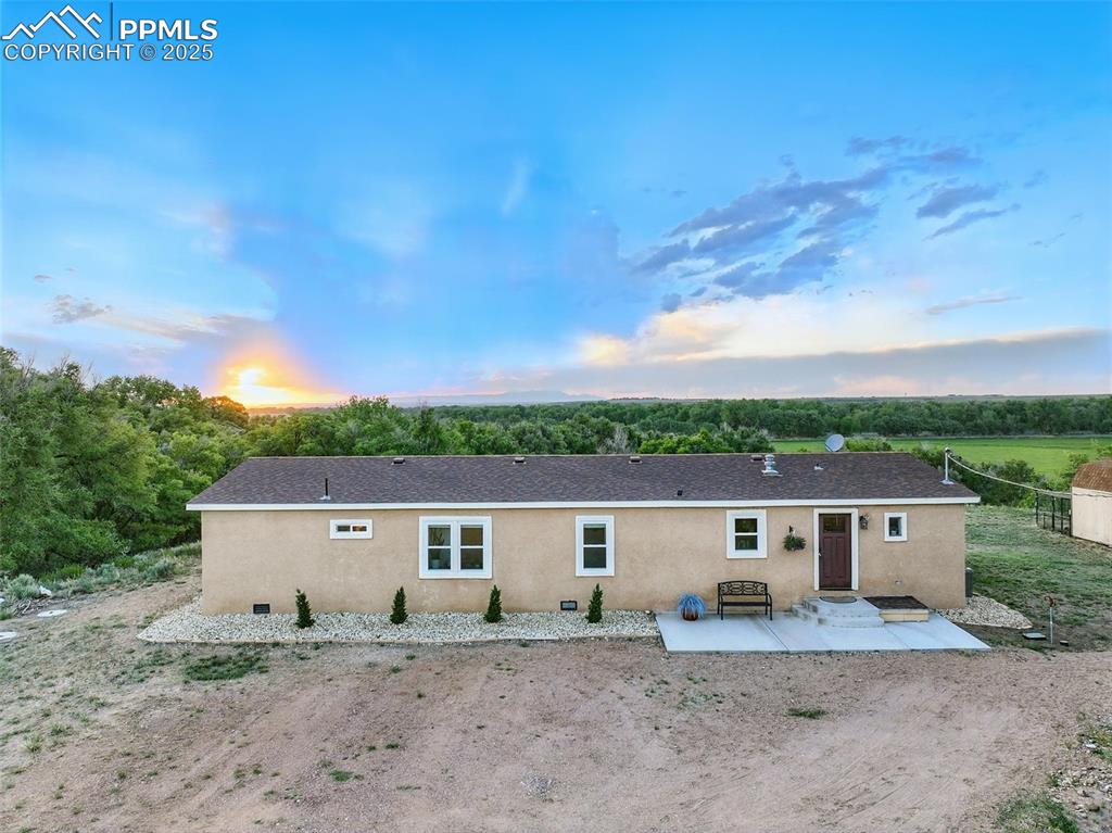 Image 2 of 45: Front of house at dusk featuring a patio and stucco siding