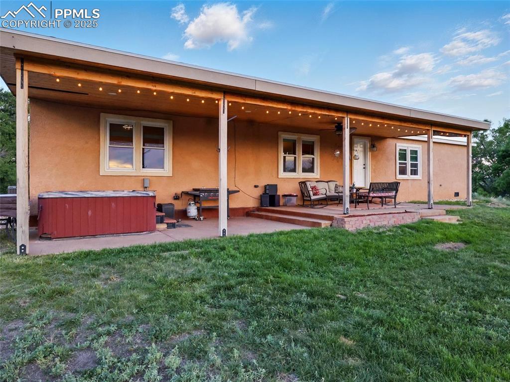 Image 32 of 45: Rear view of house featuring a hot tub, a patio area, an outdoor living spa