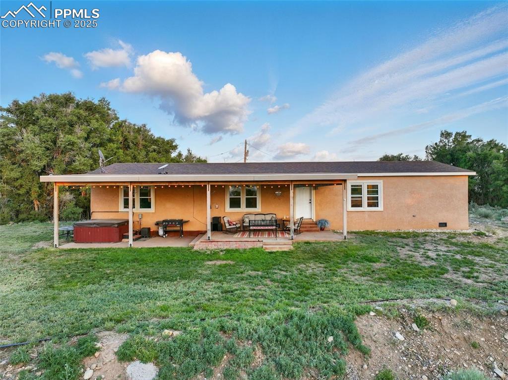 Image 4 of 45: Rear view of property featuring a hot tub, a patio, stucco siding, and a ya