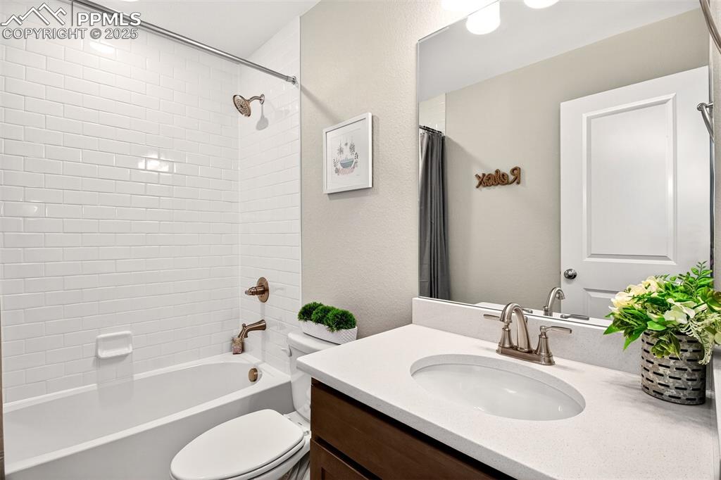 Image 19 of 29: Upstairs full bathroom with tile surround shower, Quartz countertop and des
