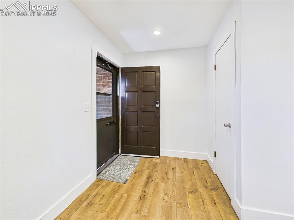 Image 2 of 50: Bright and simple entryway with recessed lighting and wide-plank wood-style