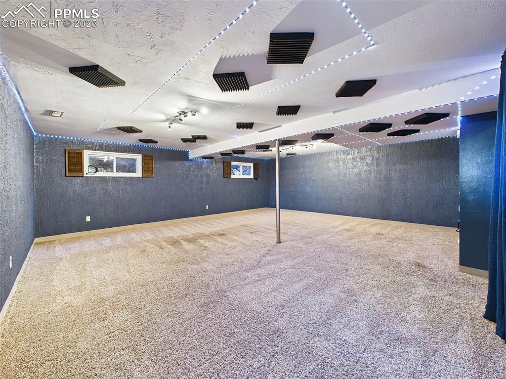 Image 22 of 50: Expansive finished basement with custom ceiling design, LED lighting, and p