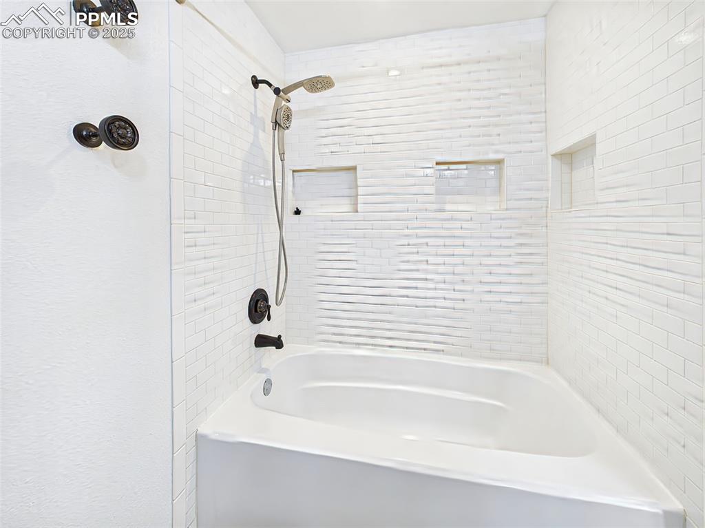 Image 36 of 50: Stylishly updated bath and shower combo with crisp white tilework, built-in