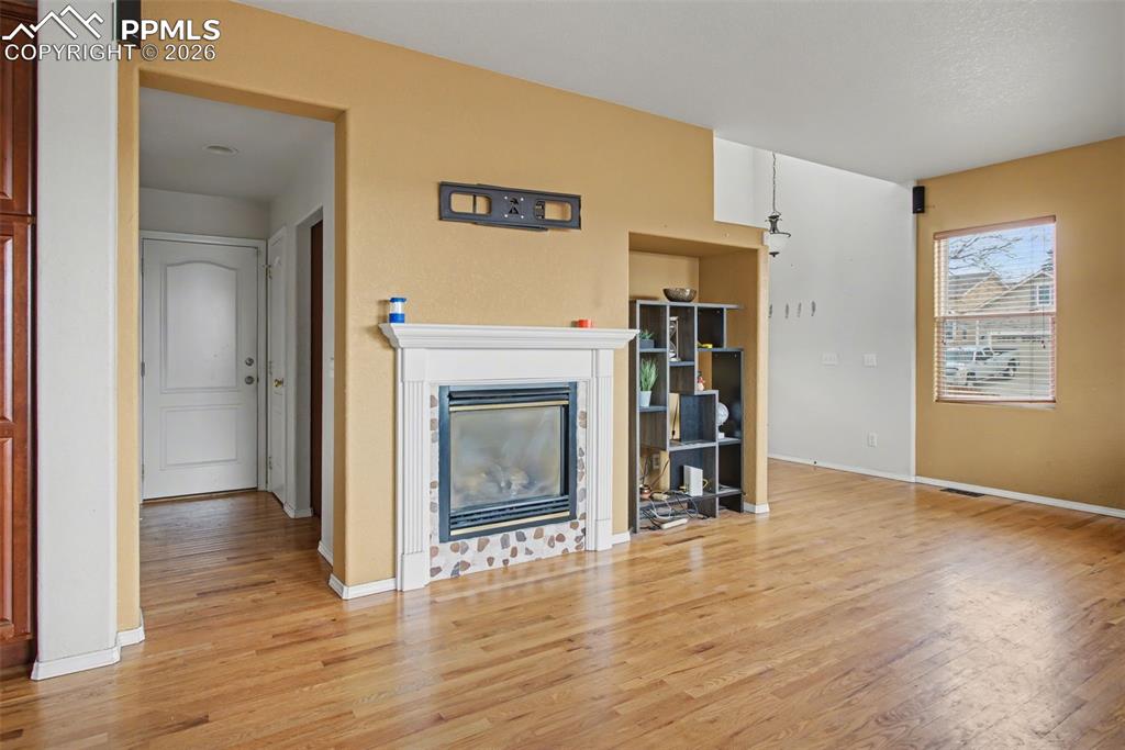 Image 14 of 33: Unfurnished living room featuring a glass covered fireplace and light wood-