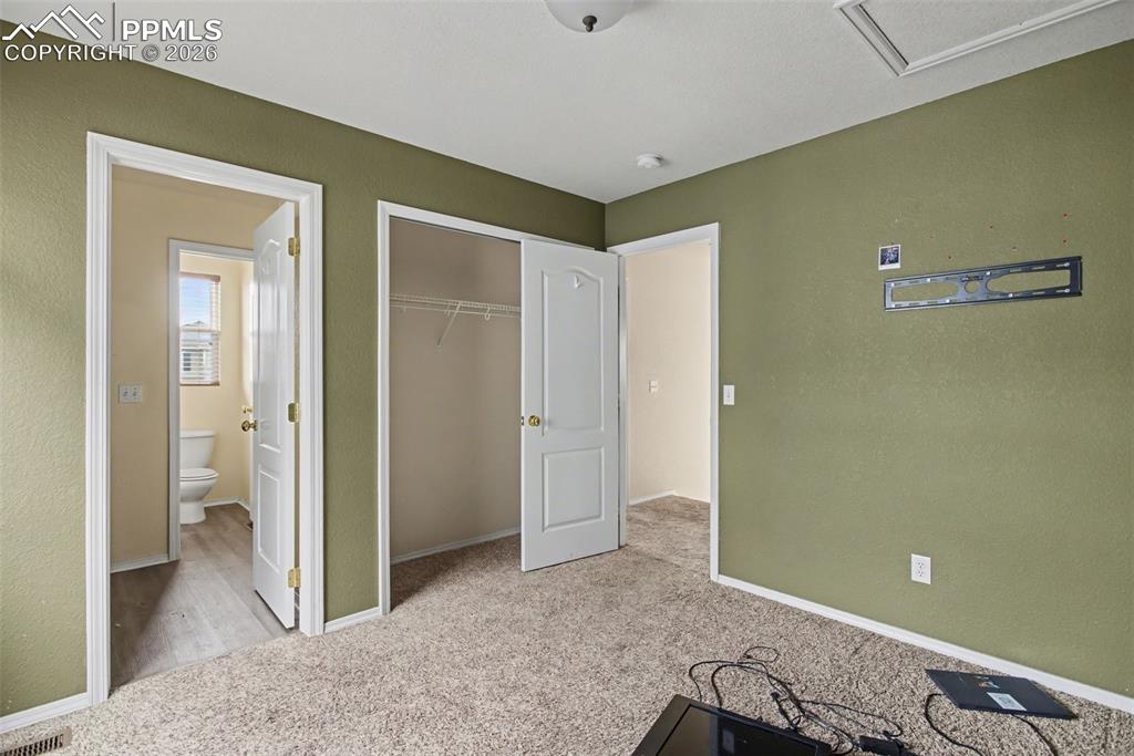 Image 23 of 33: Unfurnished bedroom with light colored carpet, a closet, and a textured wal
