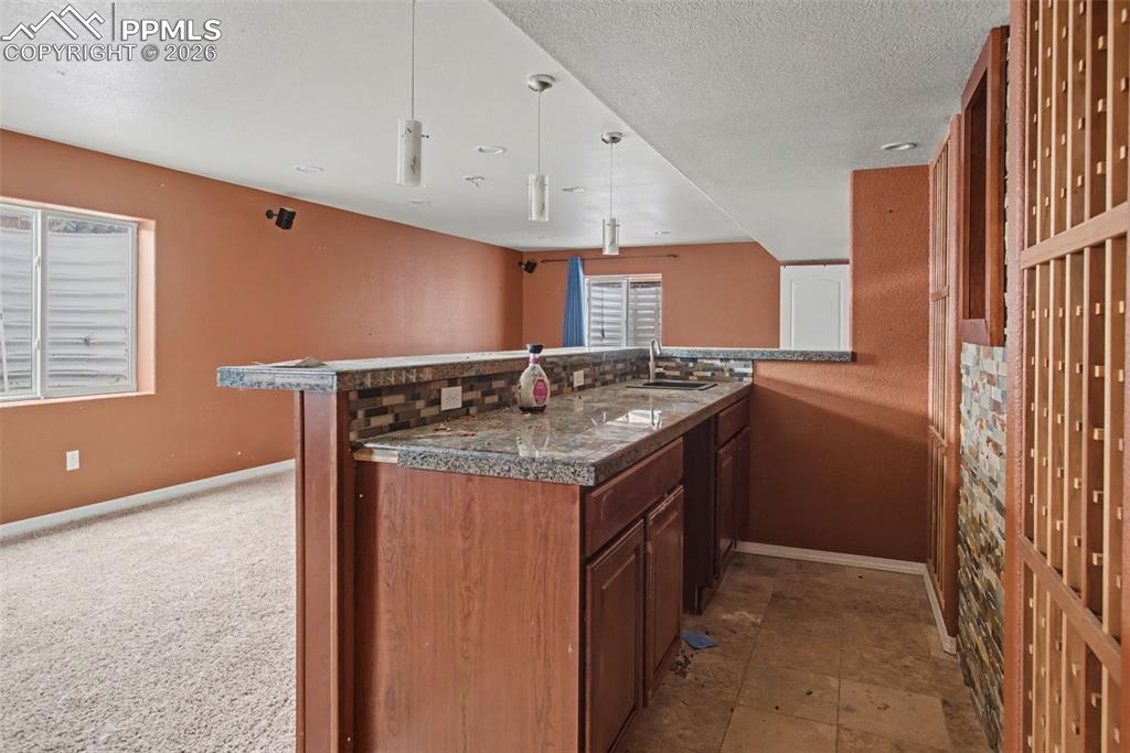 Image 27 of 33: Kitchen featuring wood finish cabinetry, a textured ceiling, pendant lighti