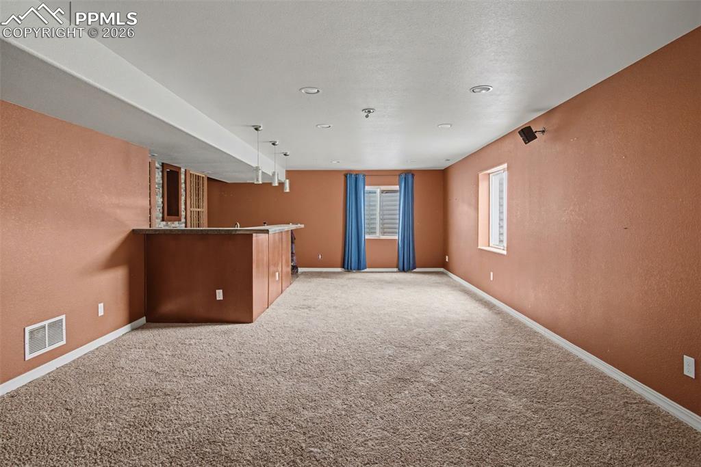 Image 29 of 33: Indoor wet bar featuring light carpet and a textured wall