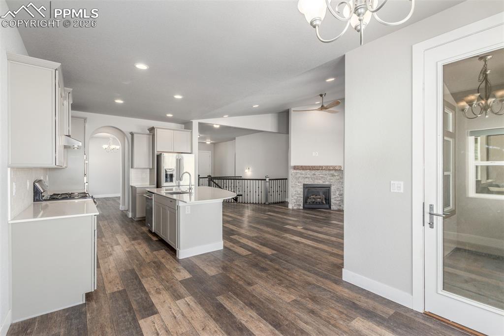 Image 10 of 46: Kitchen with a chandelier, a center island with sink, arched walkways, a fi