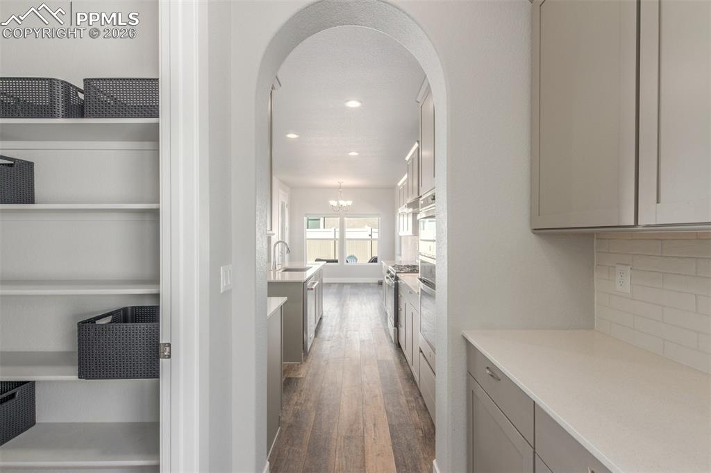 Image 12 of 46: Hallway featuring arched walkways, dark wood finished floors, recessed ligh