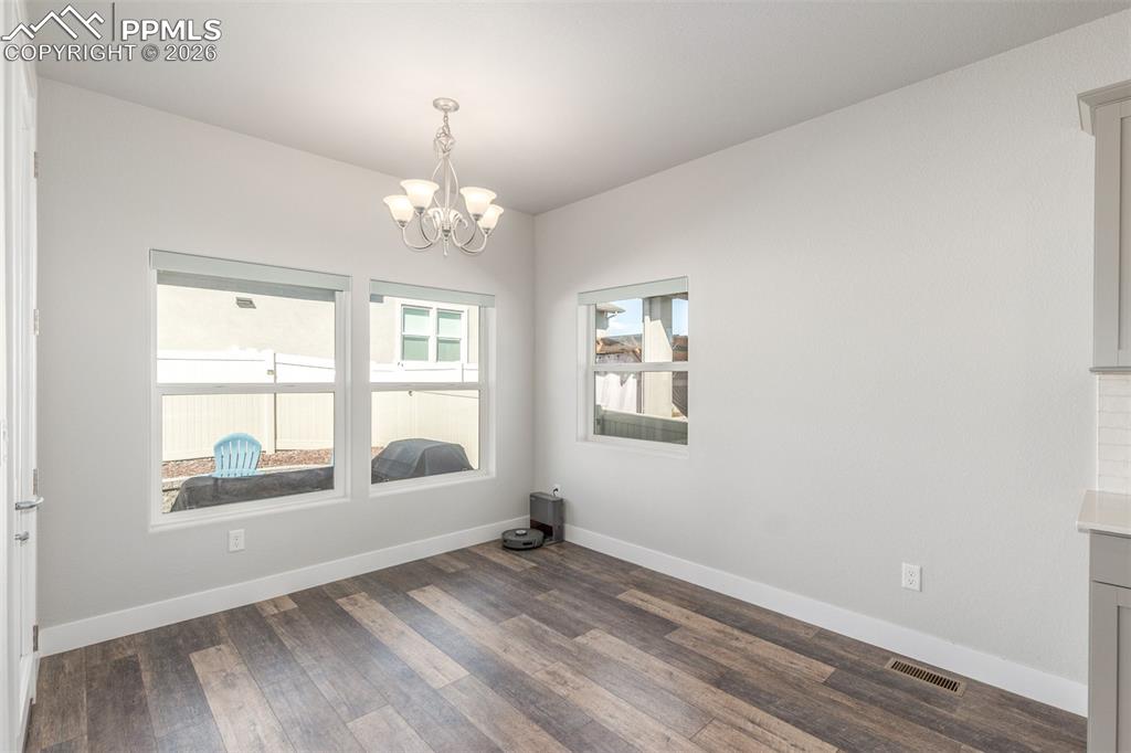Image 14 of 46: Empty room with dark wood-type flooring and a chandelier