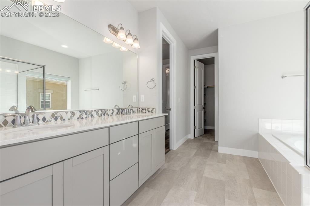 Image 18 of 46: Bathroom with double vanity, a shower, and tiled bath