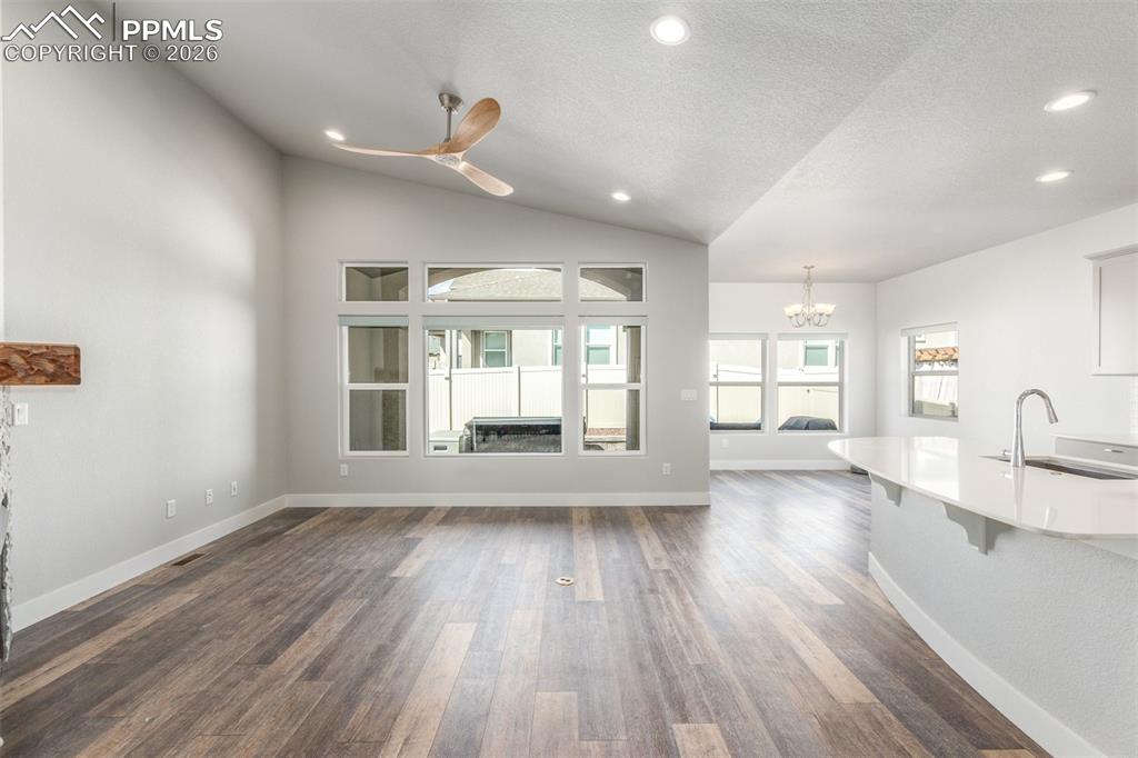 Image 4 of 46: Unfurnished living room with a chandelier, dark wood-style floors, recessed