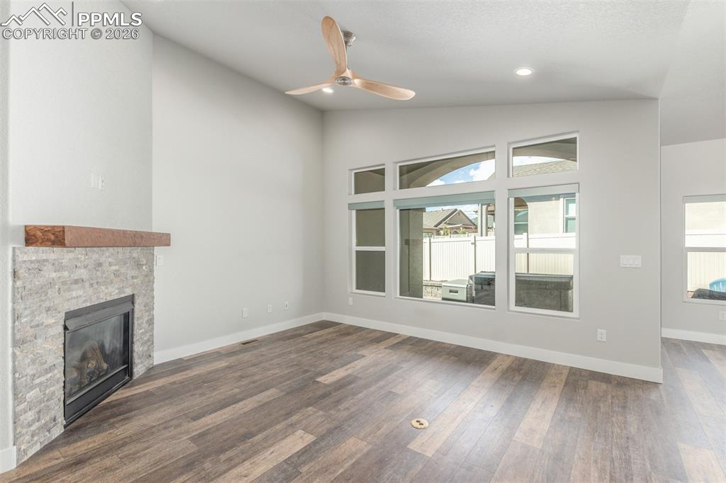Image 6 of 46: Unfurnished living room featuring a stone fireplace, dark wood-style floori