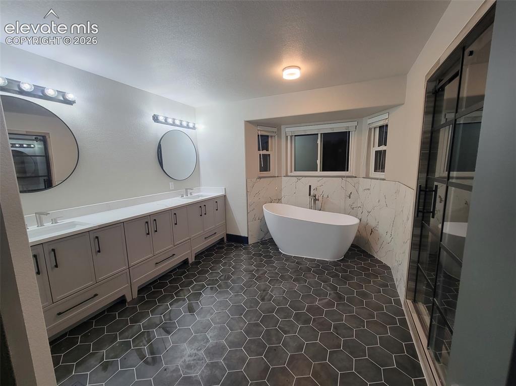 Image 46 of 47: Dual vanity with undermount sinks, hexagonal floor tiling, freestanding soa