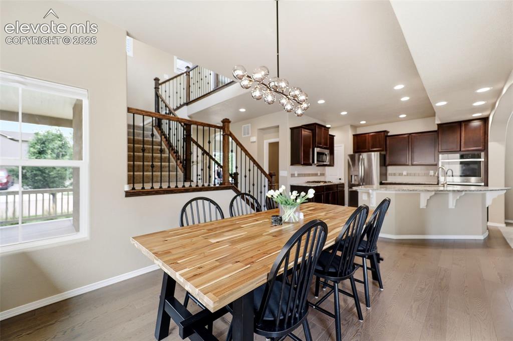 Image 10 of 48: Wood flooring throughout, with a striking open staircase featuring dark woo