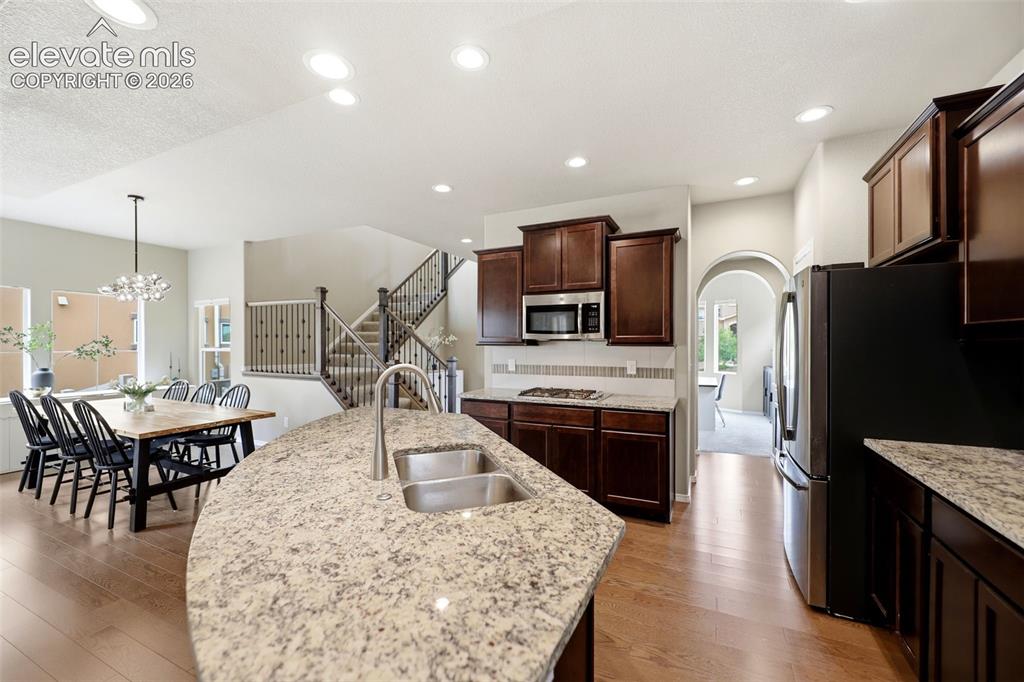 Image 11 of 48: Spacious kitchen featuring an expansive island with a double sink, dark woo