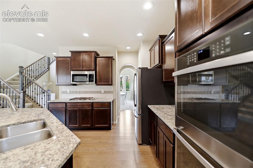 Image 12 of 48: Kitchen featuring wood flooring, dark wood cabinetry, granite countertops, 