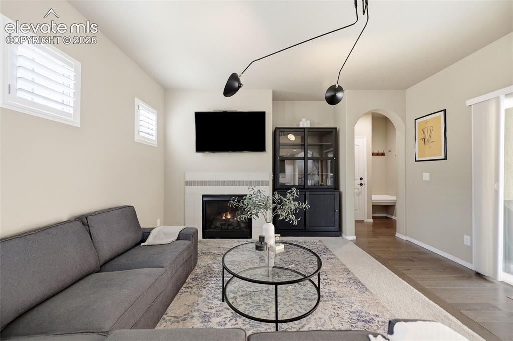 Image 14 of 48: Fireplace with mantel, cabinetry, wood flooring, sliding glass door, and ar