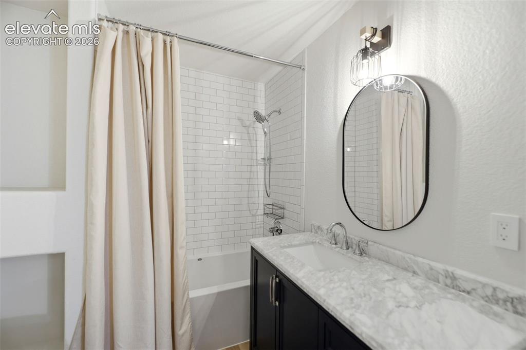 Image 23 of 48: Bathroom featuring a vanity with a white stone countertop, undermount sink,