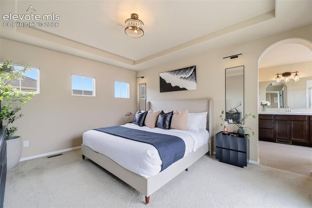 Image 29 of 48: Light and bright primary bedroom, arched doorway to primary bath
