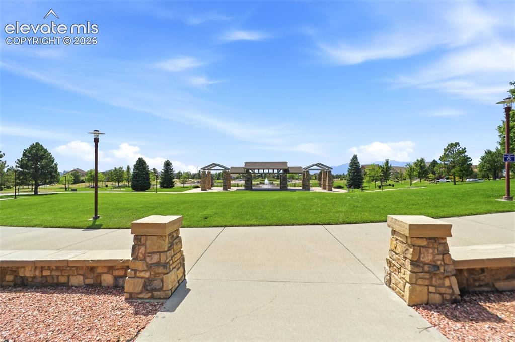 Image 43 of 48: Expansive green space featuring a central fountain, stone-clad pergolas, an