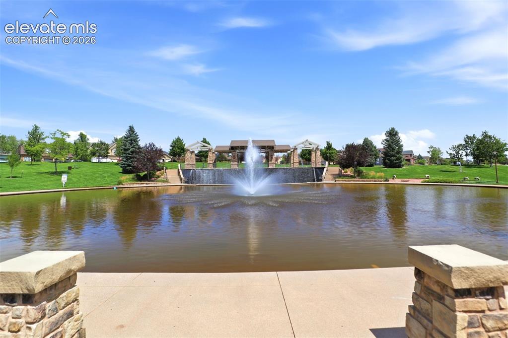 Image 45 of 48: Community pond with a central fountain feature, expansive green spaces, and