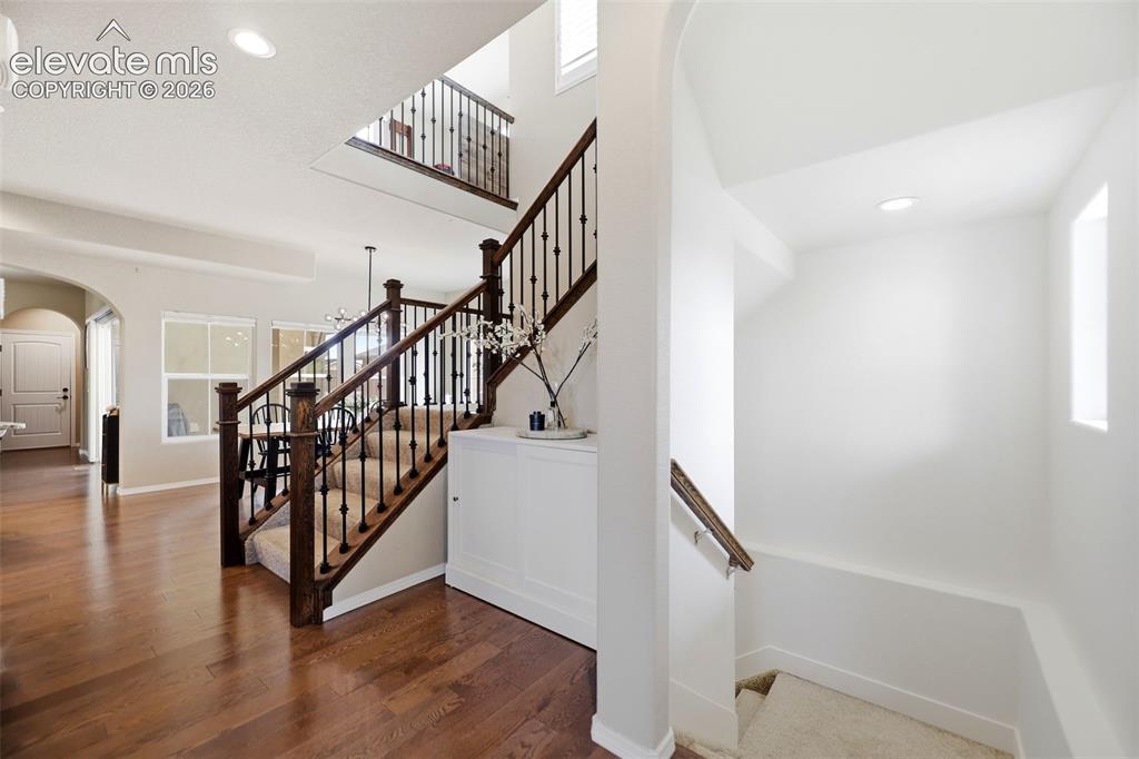 Image 6 of 48: Expansive wood flooring, two-story entryway with staircase, wrought iron ba