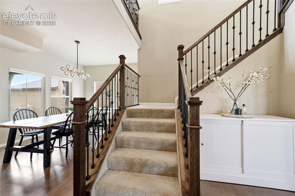 Image 8 of 48: Wood-finish flooring, carpeted staircase with wrought iron balusters, built