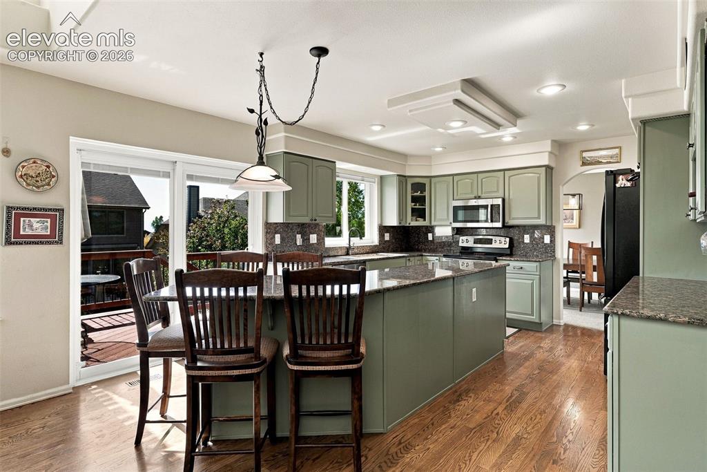 Image 11 of 50: Kitchen featuring wood-finish flooring, recessed lighting, and a center isl