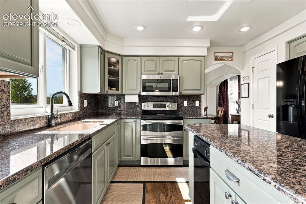 Image 12 of 50: Kitchen featuring light-toned cabinetry, stainless steel appliances, granit