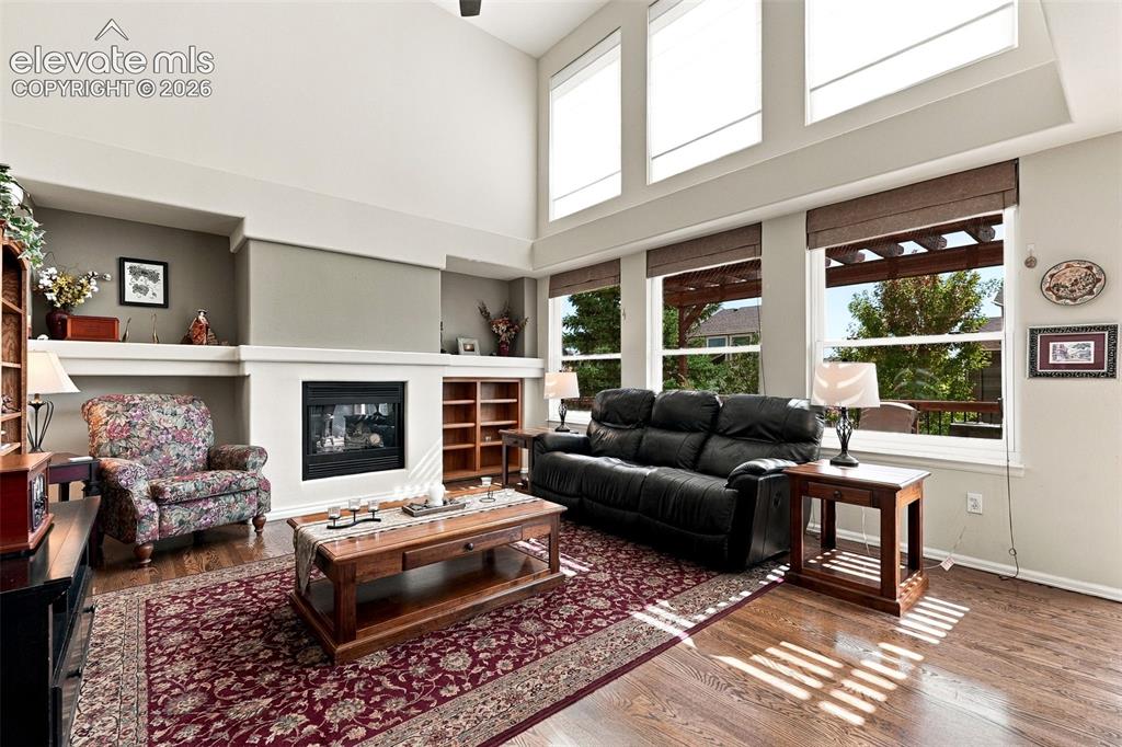 Image 16 of 50: Living area with wood-finish flooring, a fireplace with built-in shelving,