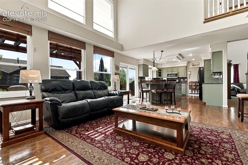 Image 17 of 50: Open-concept living space featuring wood-finish flooring, high ceilings wit