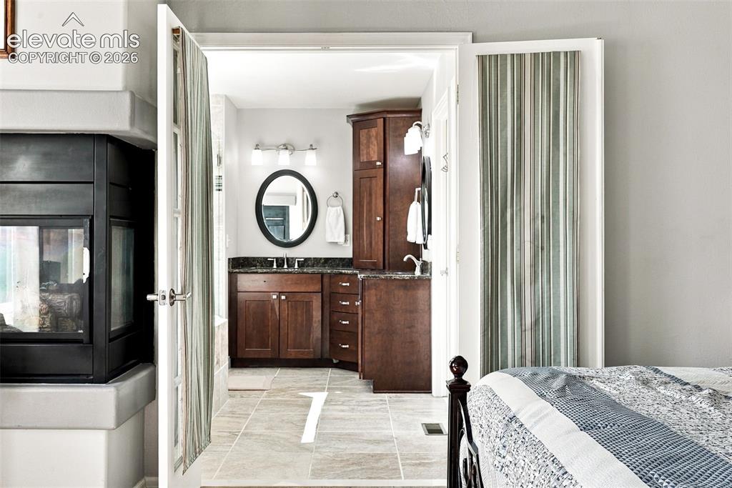 Image 20 of 50: Bathroom featuring wood cabinetry, dark countertops, a vanity mirror, and t