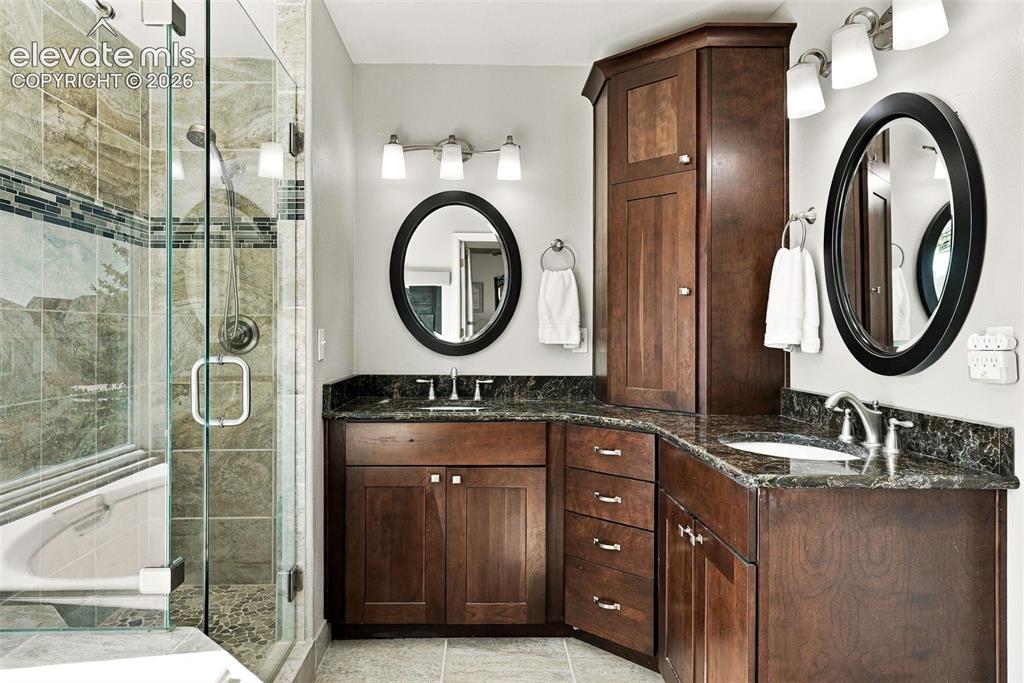 Image 22 of 50: Dual vanity with dark wood cabinetry and stone countertops