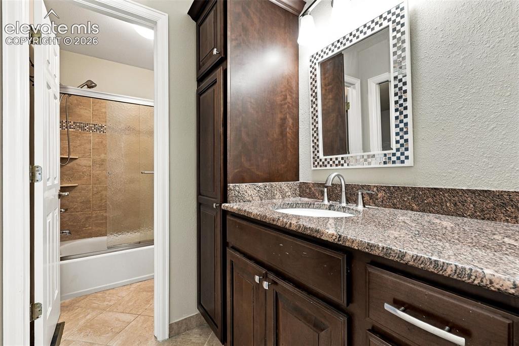 Image 27 of 50: Vanity with a granite countertop, undermount sink, and chrome faucet