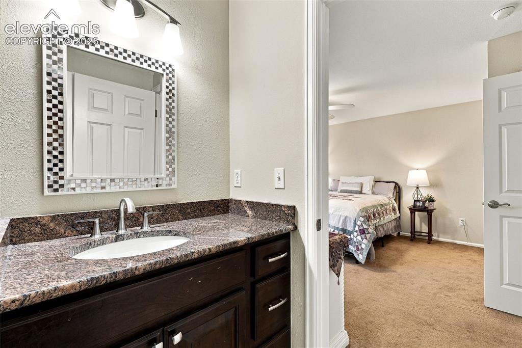 Image 29 of 50: Dark wood-finish vanity with an undermount sink, a granite countertop, and