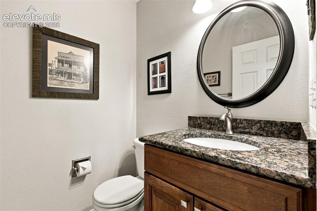 Image 35 of 50: Vanity featuring a dark stone countertop, undermount sink, and wood-finish 