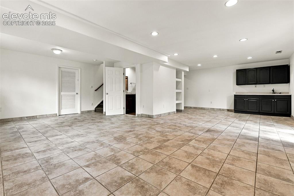 Image 37 of 50: Spacious area featuring tile flooring, recessed lighting, built-in shelving