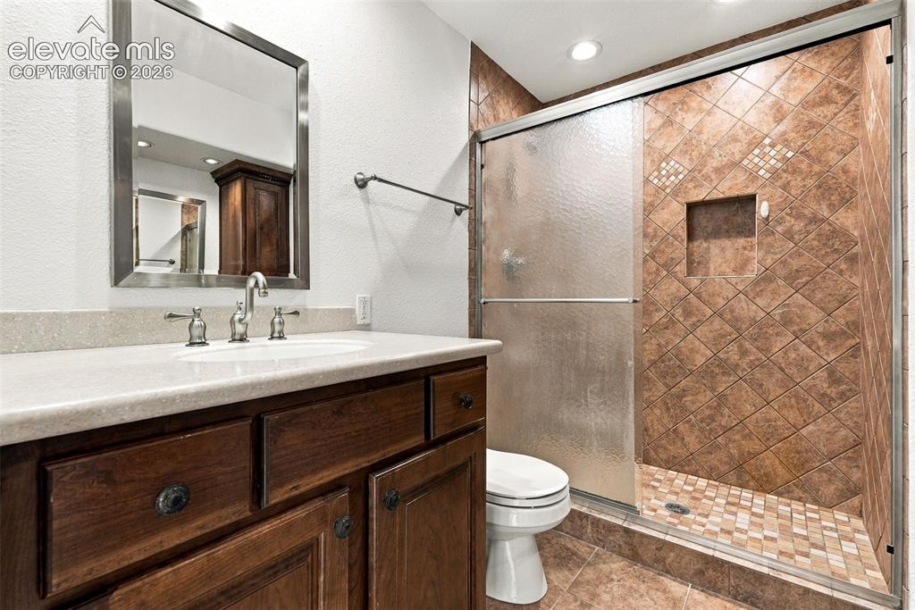 Image 38 of 50: Walk-in shower with tiled walls and floor, built-in shower niche, and a gla