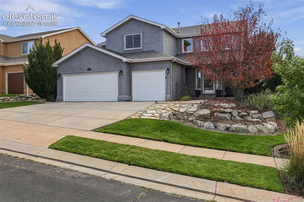 Image 4 of 50: Stucco exterior with a pitched shingle roof, two-car garage, concrete drive