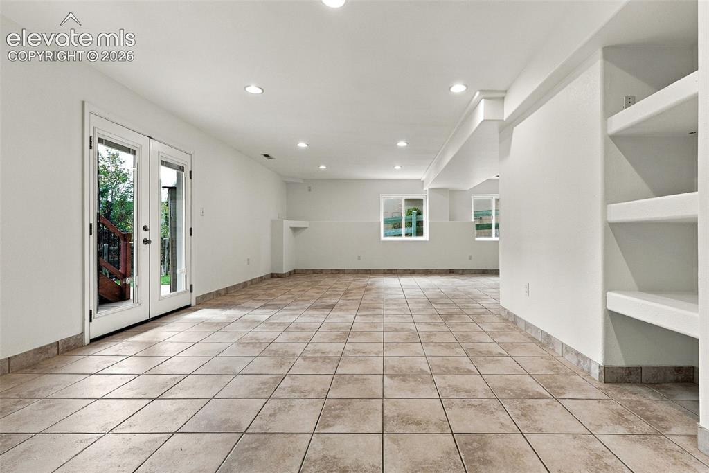 Image 40 of 50: Spacious room featuring tile flooring, recessed lighting, built-in shelving