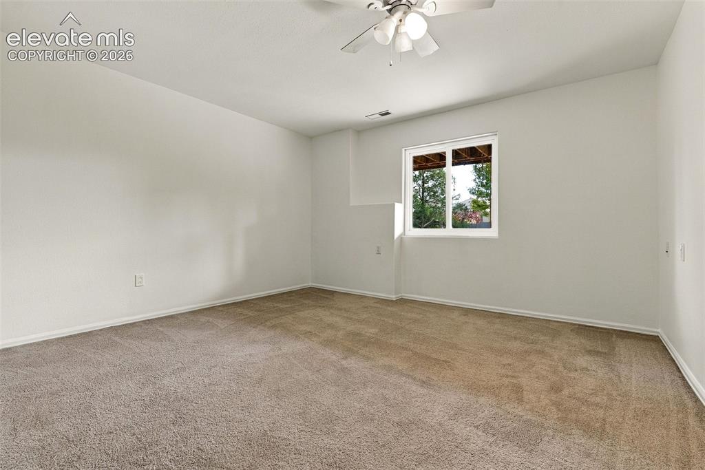 Image 42 of 50: Wall-to-wall carpeting, white painted walls, ceiling fan, and a window with