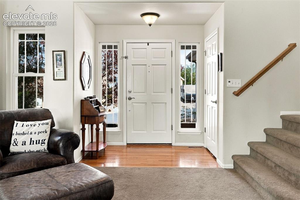 Image 6 of 50: Entry features a paneled white door with side light windows, wood-finish fl