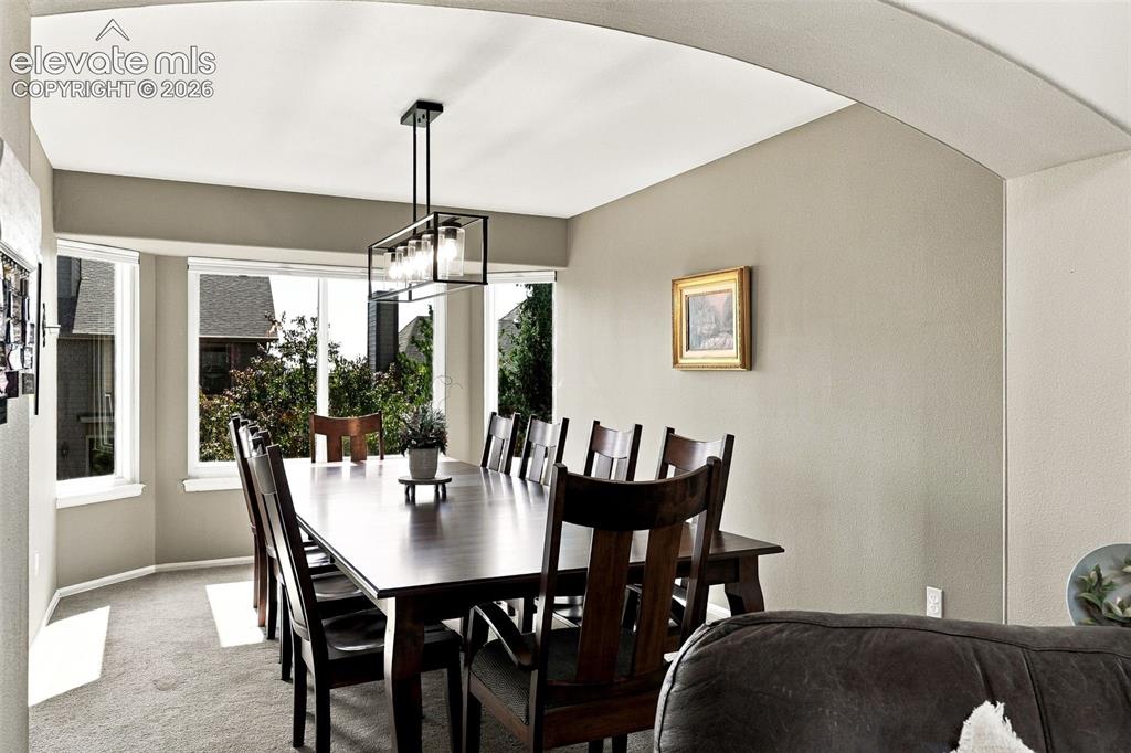 Image 9 of 50: Bay window with multiple panes, modern linear chandelier, and archway entry