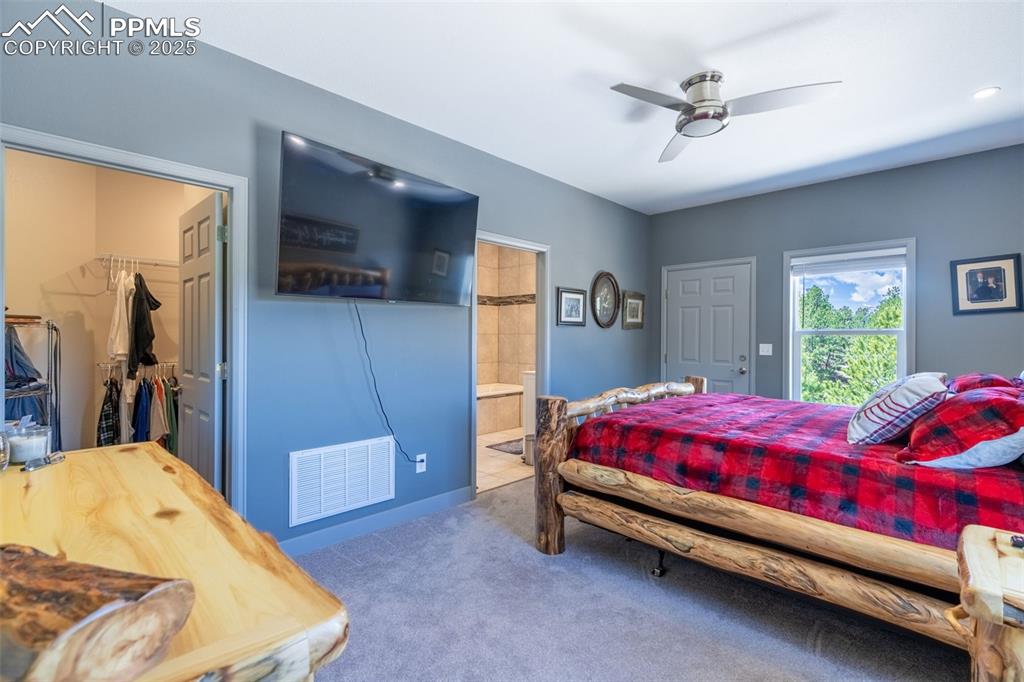 Image 12 of 41: Bedroom featuring carpet, a spacious closet, ensuite bath, ceiling fan, and