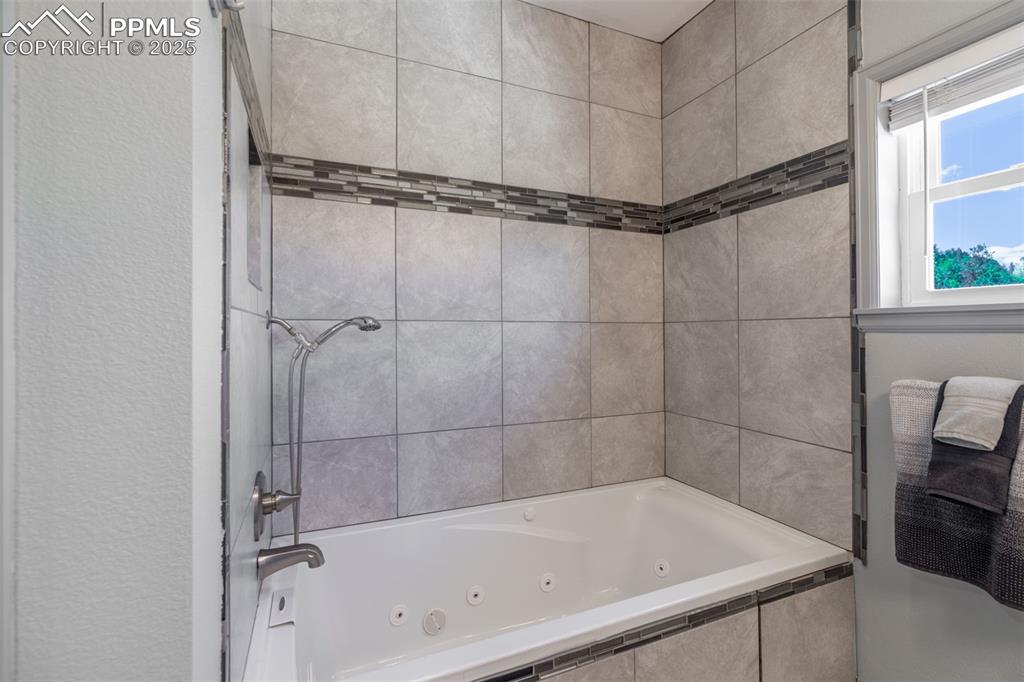 Image 16 of 41: Full bathroom featuring a combined bath / shower with jetted tub and a text