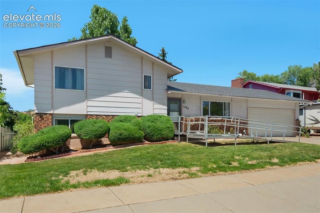 Image 1 of 25: Split-level residence featuring a light-colored siding exterior with a bric