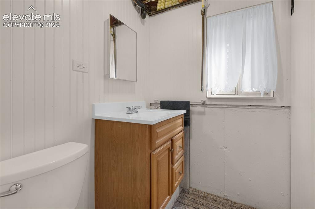 Image 14 of 25: Bathroom featuring a single vanity with wood-finish cabinetry, white counte